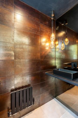 a room with a wooden wall with a sink and lights at Riverside Villas in Manchester