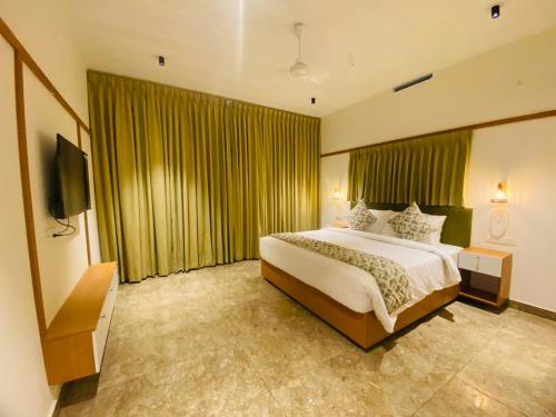 a hotel room with a bed and a television at Misty Glen in Vagamon
