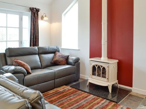 a living room with a leather couch and a fireplace at Gelli Hir in Bronant
