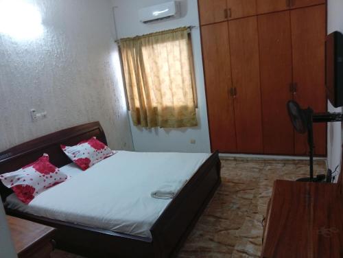 a bedroom with a bed with red pillows and a window at Johannys'co in Abidjan