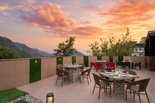 a patio with tables and chairs and a sunset at Hotel LA Eden in Mussoorie