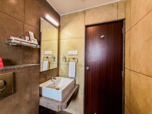 a bathroom with a sink and a wooden door at Zip By Spree Hotels Kolhapur in Kolhapur