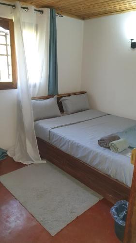 a large bed in a room with a window at Chez Rasoa Andasibe in Moramanga