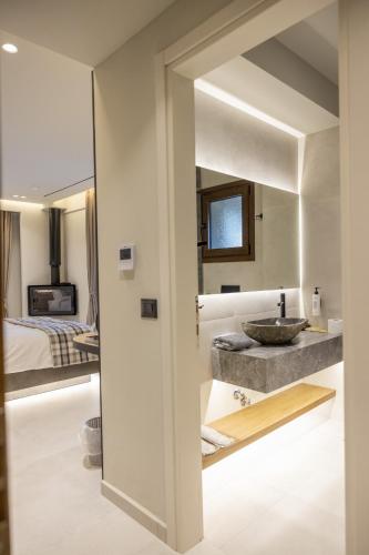 a bathroom with a sink and a bedroom at Polyzos Luxury Suites Meteora #6 - Adults Friendly in Kalabaka