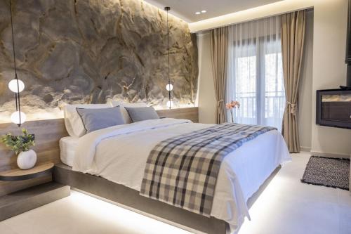 a bedroom with a large bed and a stone wall at Polyzos Luxury Suites Meteora #6 - Adults Friendly in Kalabaka