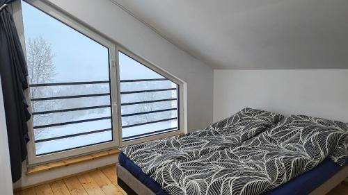 a bedroom with a bed and a large window at Domki Mała Tresna in Bierna