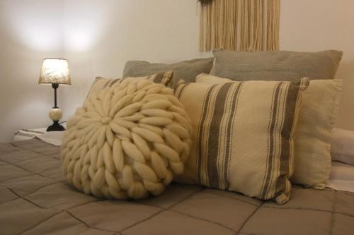 a bed with a pile of pillows next to a lamp at Lo de Ine in La Cumbre