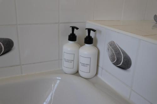two white bottles sitting on the edge of a bath tub at La Solitude in Bois-de-Cené