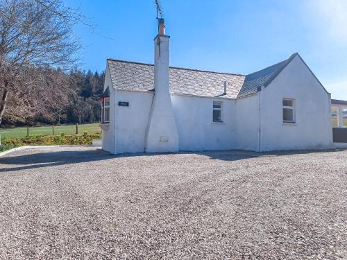a white church with a tower on a gravel driveway at Ivy Cottage in Mountblairy