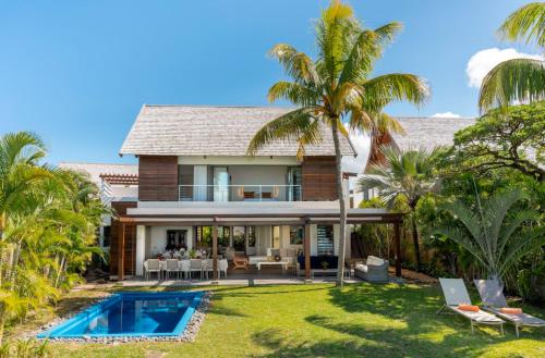 a house with a swimming pool and palm trees at Ruby in Post of Flacq