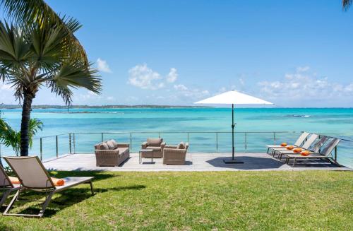 a patio with chairs and an umbrella and the ocean at Ruby in Post of Flacq