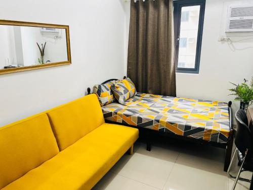 a living room with a yellow couch and a bed at Tower1 Smdc green2 Dasmarinas in Dasmariñas