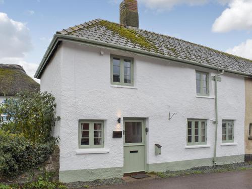 a white house with a green door at Welcome Cottage in Woolfardisworthy