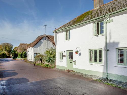 a white house with a green door on a street at Welcome Cottage in Woolfardisworthy