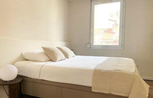 a bedroom with a bed with white sheets and a window at Le petit Berriat - Grenoble centre in Grenoble