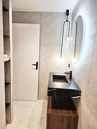 a bathroom with a black counter and a white door at Le petit Berriat - Grenoble centre in Grenoble