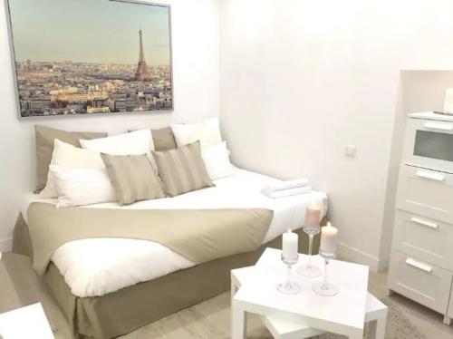 Cette chambre blanche comprend un lit et une table avec des bougies. dans l'établissement Appartements Haussman Lafayettes, à Paris