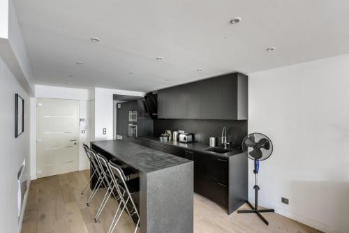 une cuisine avec des armoires noires et un comptoir noir dans l'établissement Appartements Haussman Lafayettes, à Paris