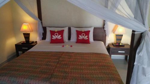a bedroom with a bed with red pillows at Frangipani Beach Hotel in Lovina
