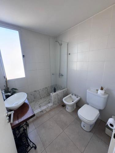 a white bathroom with a toilet and a sink at Beautiful fully-equipped duplex in Ezeiza
