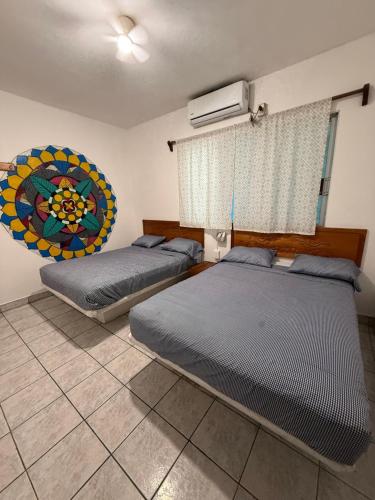 a bedroom with two beds and a window and a mirror at Casa de las Iguanas Tecolutla in Tecolutla