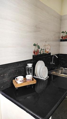 a kitchen with a counter top with a sink and dishes at The Prime Residences of Samuels Comfort Homes in Bangalore