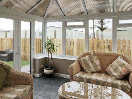 a conservatory with a couch and a table and windows at Firth Lodge in Mainsriddle