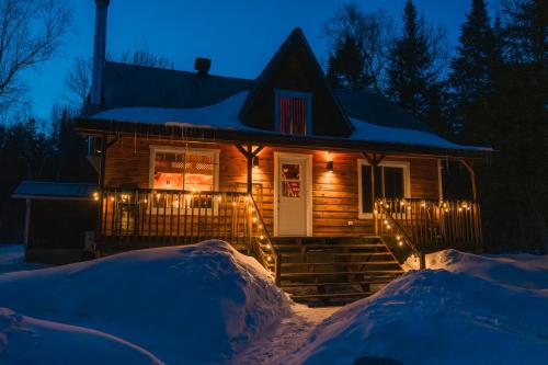 a house with christmas lights in the snow at Repère de la Rivière - Bord de l'eau- Activités nautiques in Saint-Alexis-des-Monts