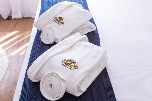 two white towels are sitting on a bed at Hotel Chateau in Campos do Jordão