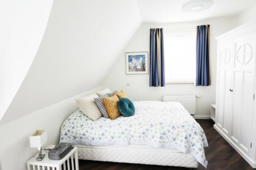 a white bedroom with a bed and a window at Ferienhaus Dwarslöper mit Sauna und Garten in Fuhlendorf in Fuhlendorf