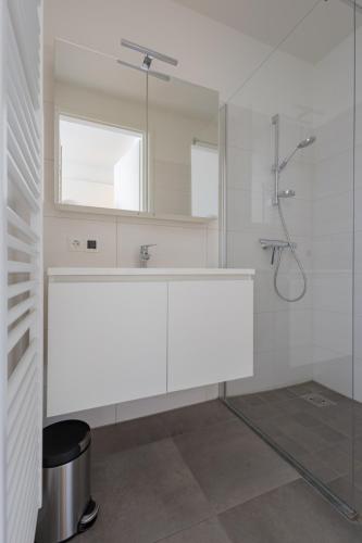 a white bathroom with a sink and a mirror at Duinhof IX E204 in Cadzand