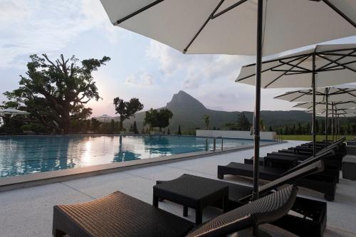 a pool with chairs and umbrellas with a mountain in the background at Gloria Manor in Kenting