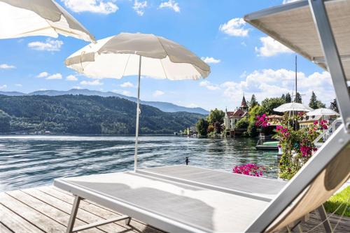 a table with an umbrella on a dock next to the water at Hotel Nikolasch mit eigenem Seebad - Adults Preferred in Millstatt