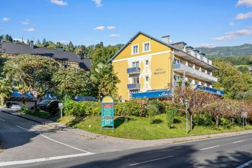 a yellow building on the side of a street at Hotel Nikolasch mit eigenem Seebad - Adults Preferred in Millstatt