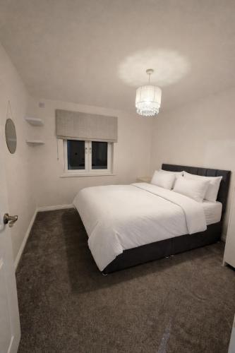 a bedroom with a large white bed with a chandelier at Spacious 2BR with ensuite and AC unit and balcony near Heathrow in Cranford