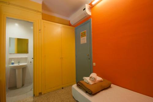 łazienka z pomarańczowymi ścianami i łóżkiem z kapeluszem w obiekcie Studio Hostel w Barcelonie