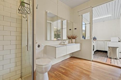 a white bathroom with a toilet and a sink at Tiny house at Gilderoy Valley Views in Yarra Junction