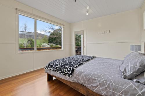 a bedroom with a bed and a large window at Tiny house at Gilderoy Valley Views in Yarra Junction