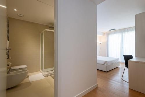 a bathroom with a toilet and a bed in a room at UNA Hotels Le Terrazze Treviso Hotel & Residence in Villorba