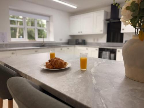 a table with a plate of food and two glasses of orange juice at Low Street Escape 3 Bed, Sleeps 9, Gated Drive, WiFi, Contractors in Great Wyrley