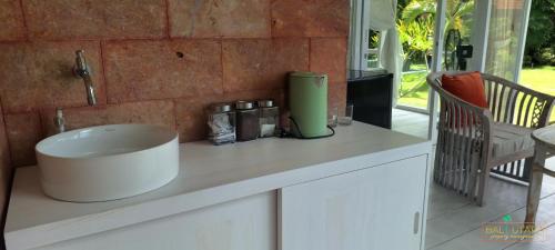 a kitchen counter with a sink on a counter top at Rumah Putih Beachfront Bungalow in Tegallengah