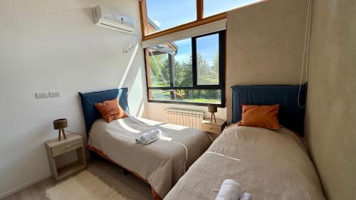 two beds in a small room with a window at Cabañas Indómita in El Bolsón