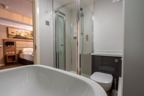a bathroom with a bath tub and a toilet at Riverside Hotel in Cirencester