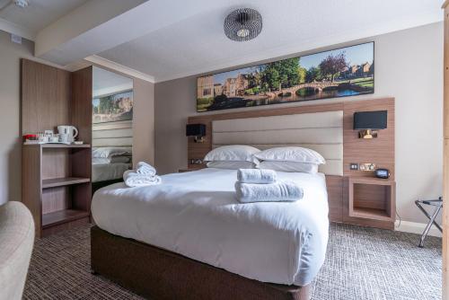 a bedroom with a large bed with a large headboard at Riverside Hotel in Cirencester