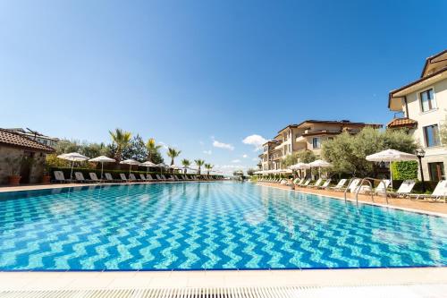 a large swimming pool with chairs and umbrellas at Burgas Beach Resort Apartments in Burgas