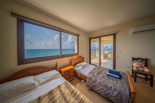a bedroom with two beds and a large window at Infinity Blue Villa w Pool in Pomos