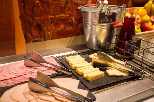 a plate of cheese and utensils on a counter at ibis Bordeaux Centre Gare Saint Jean Euratlantique in Bordeaux