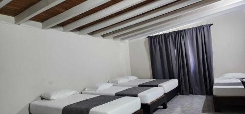 two twin beds in a room with a window at Hotel Distrito Unicentro in Medellín