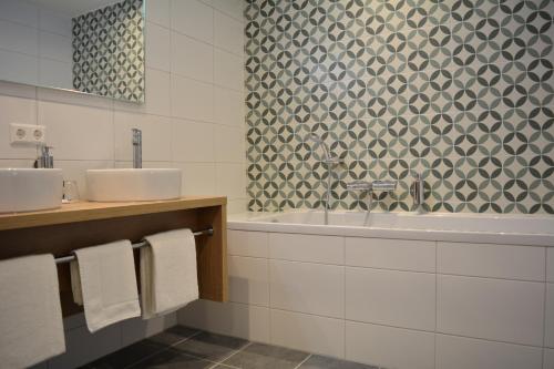 a bathroom with two sinks and a bath tub at Fletcher Strandhotel Haamstede in Burgh Haamstede