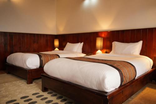 two beds in a room with wooden walls at Yangkhil Resort in Tongsa